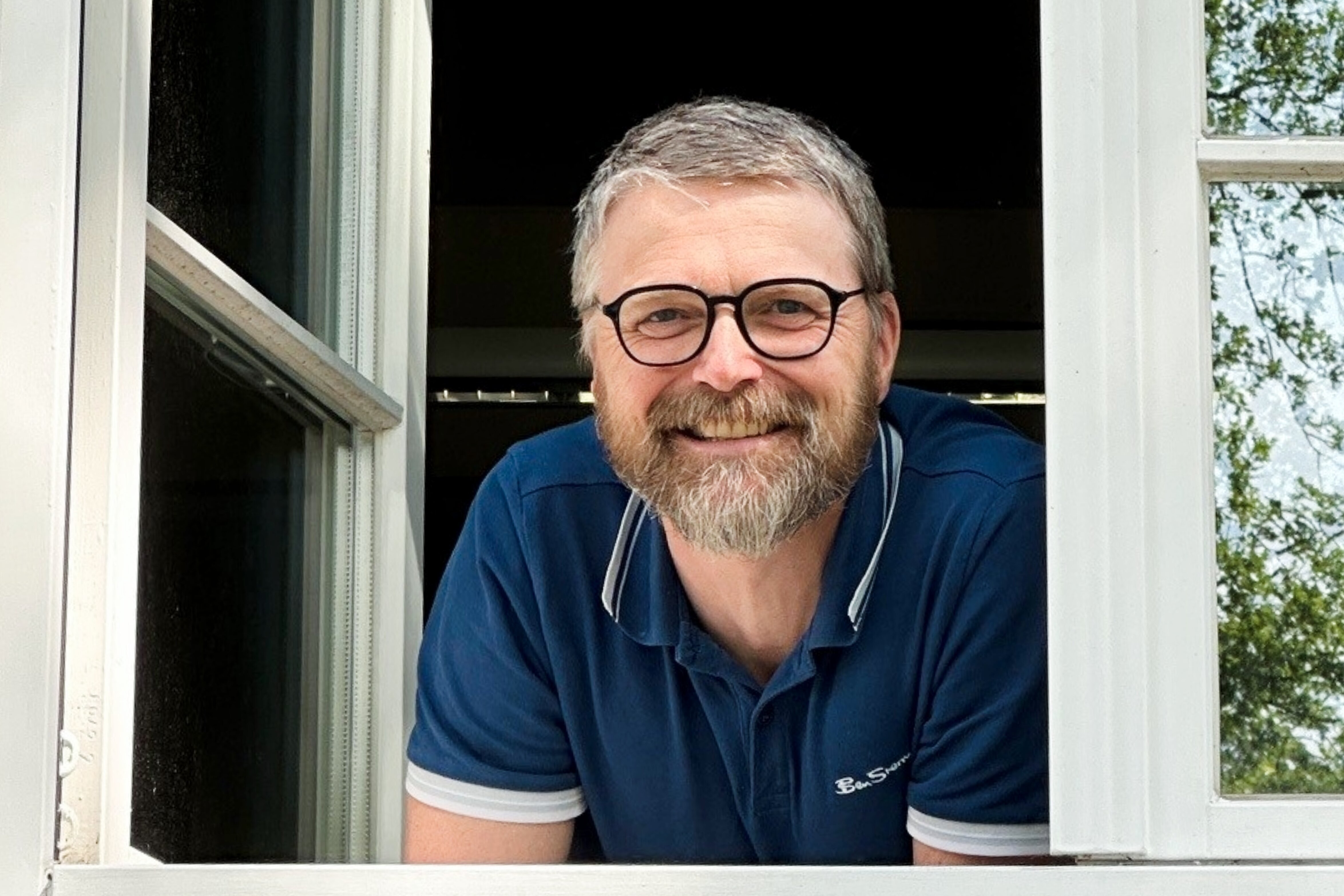Mann schaut lächelnd aus dem Fenster