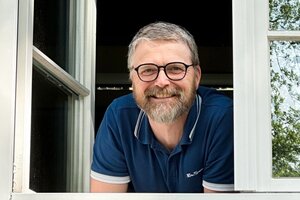 Mann schaut lächelnd aus dem Fenster