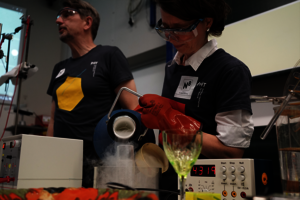 Eine Wissenschaftlerin gießt eine dampfende Flüssigkeit in ein Reagenzglas.