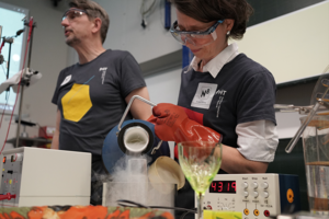 Eine Wissenschaftlerin gießt eine dampfende Flüssigkeit in ein Reagenzglas.