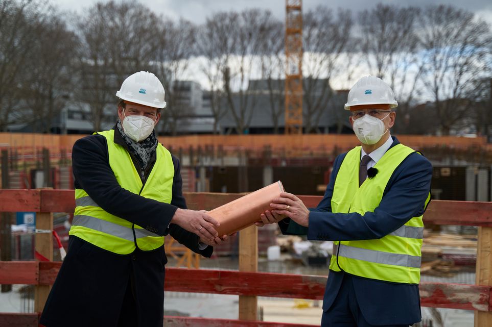 Prof. Dr. Werner Ullmann und Prof. Kai Kummert mit der Zeitkapsel, die im Baufeld versenkt wurde