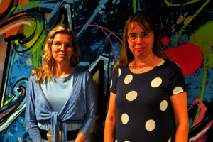 Zwei Frauen vor einer Graffiti-Wand.