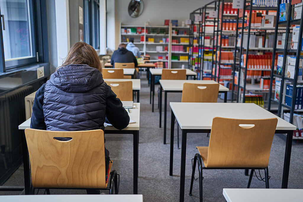 Einzeltische zur Stillarbeit, daneben Bücherregale