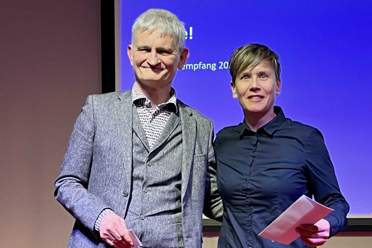 Zwei Personen stehen nebeneinander auf einer Bühne