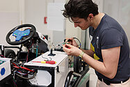 Ein junger Mann lötet an einem Elektrokart