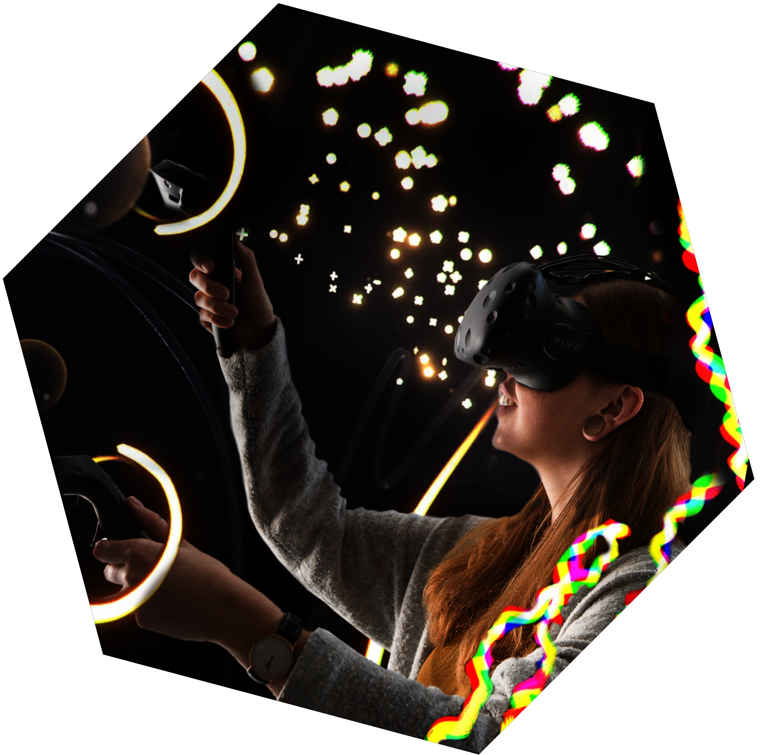 Eine Person trägt eine VR-Brille und hält in beiden Händen Controller in die Luft. Um sie herum sind Seifenblasen, Luftschlangen und Funken.