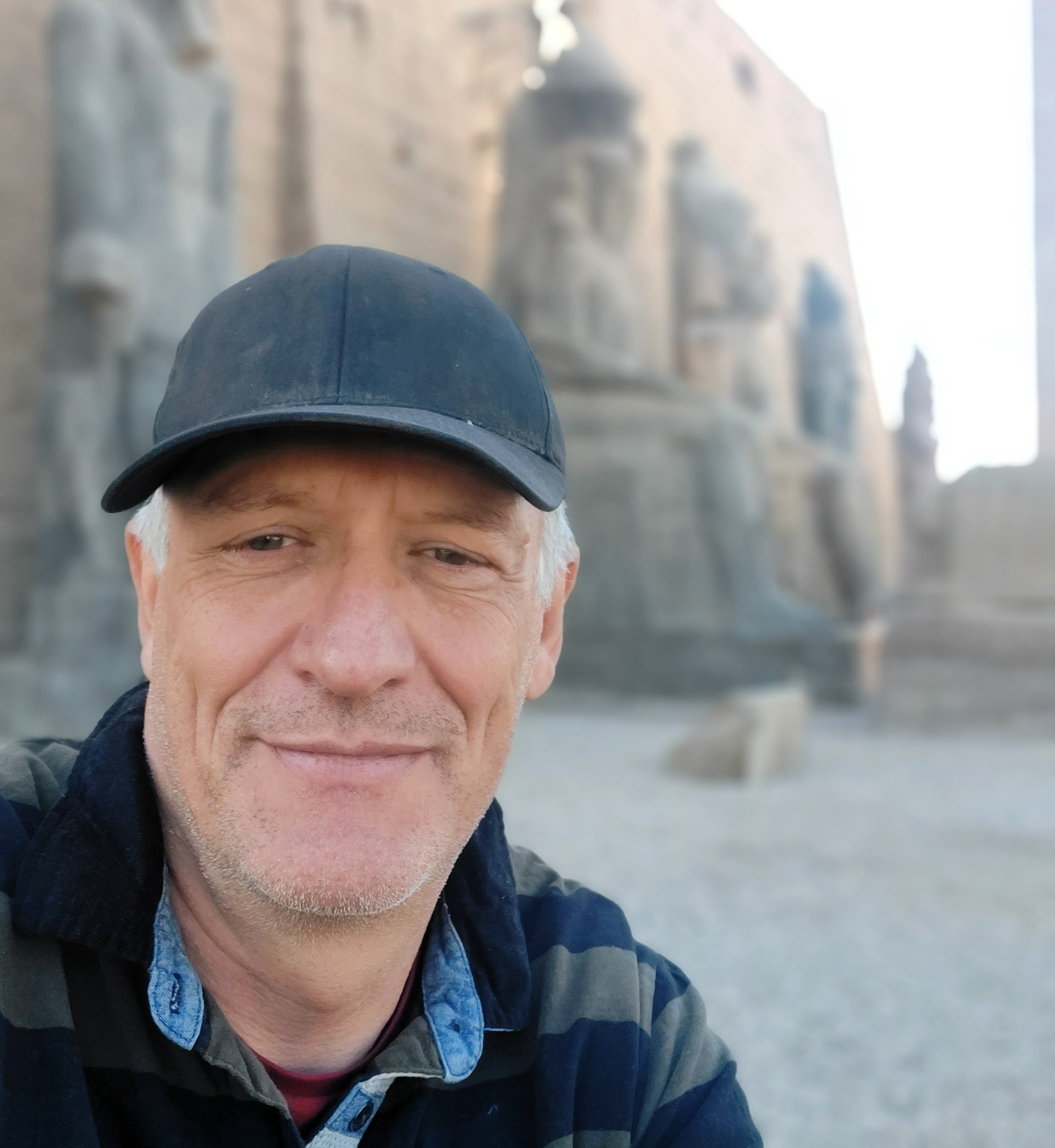 Mann mit Basecap macht Selfie vor einer Tempel-Ruine