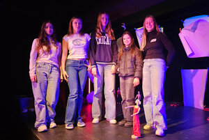 Vier Mädchen posieren auf einer Bühne in bläulichem Licht