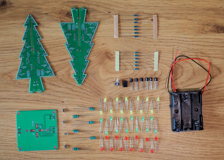 Ausgebreitete Einzelteile eines Bausatzes für LED-besetzte Leiterplatten in Form von Weihnachtsbäumen