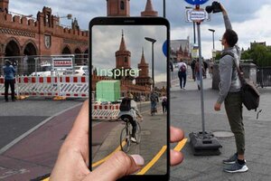 Auf dem Handy-Kamerabild ist ein 3D-Modell eines geplanten Bauwerks eingeblendet, im Hintergrund die Umgebung, wo das Bauwerk entstehen soll.