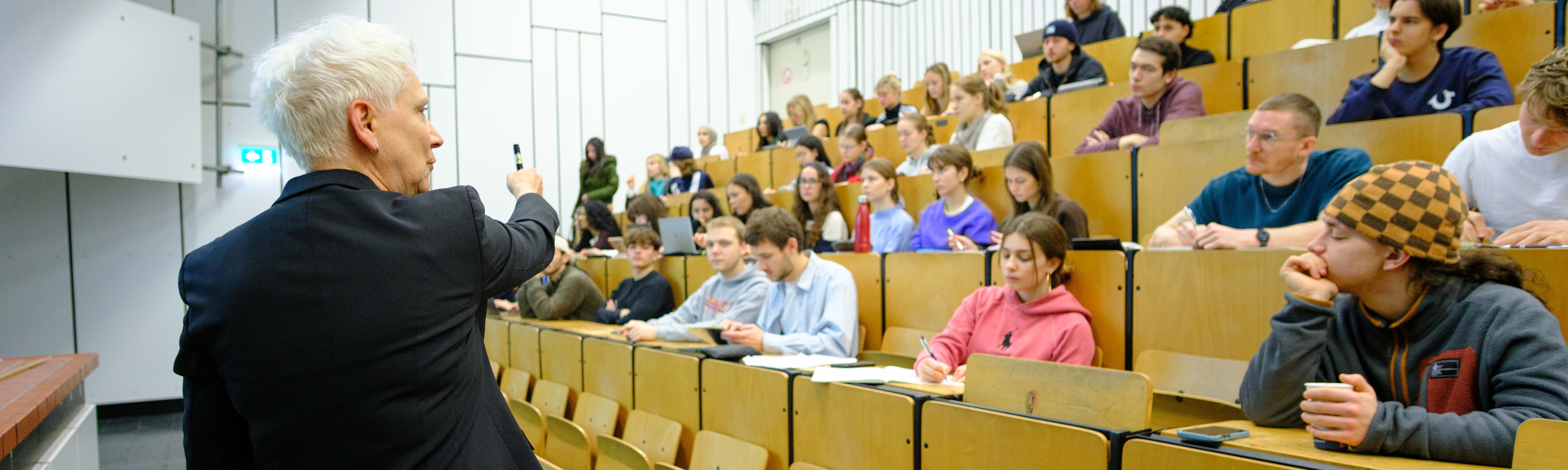 Professorin spricht zu Studierenden im Hörsaal