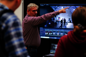 Dr. Frank Merkle vom Deutschen Herzzentrum Berlin steht vor einem Display, auf dem eine VR-Anwendung zu sehen ist und hält einen Vortrag.