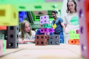 Menschen betrachten Modelle aus bunten Bausteinen