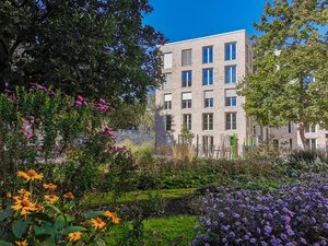 Gebäude der BHT-Kita, davor blühende Staudengewächse