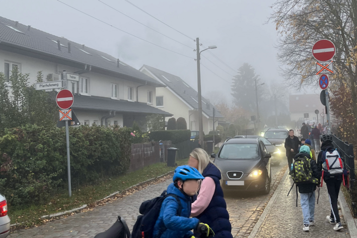 Zwei Kinder schieben an einem nebligen Tag entgegen der Fahrtrichtung in eine enge Einbahnstraße mit Kopfsteinpflaster