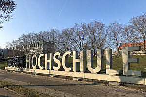 Ehemaliger Schriftzug der Beuth Hochschule aus Betonbuchstaben auf dem Campus, das Wort "Beuth" ist verhüllt