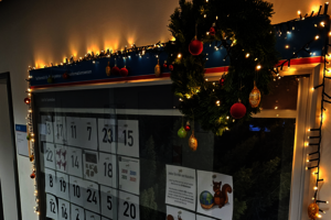 Adventskalender mit 24 Türchen in einer Glasvitrine, die weihnachtlich geschmückt ist.