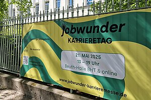 Banner mit Schriftzug "Jobwunder Karrieretag" befestigt an einem Zaun auf dem BHT-Campus