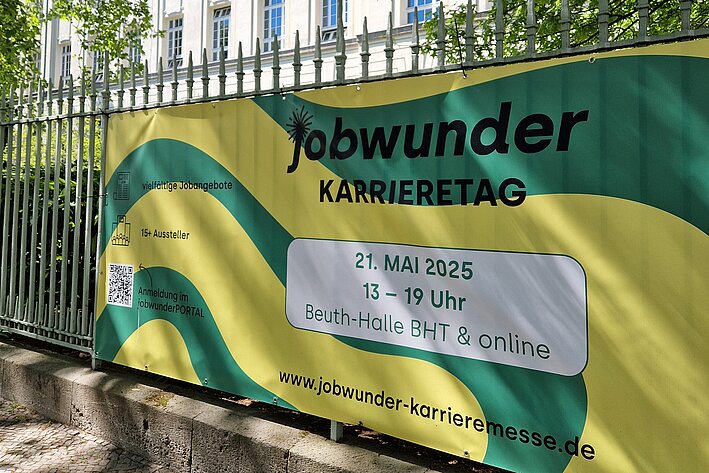 Banner mit Schriftzug "Jobwunder Karrieretag" befestigt an einem Zaun auf dem BHT-Campus