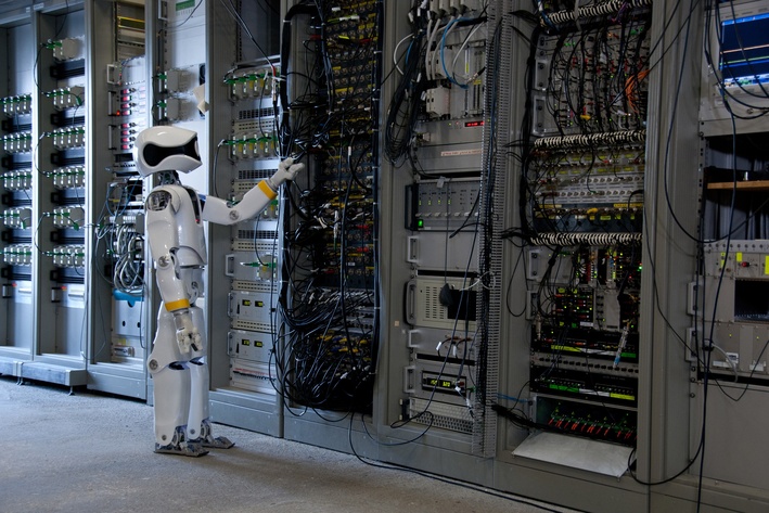 Ein humanoider Roboter steht vor mehreren Serverschränken