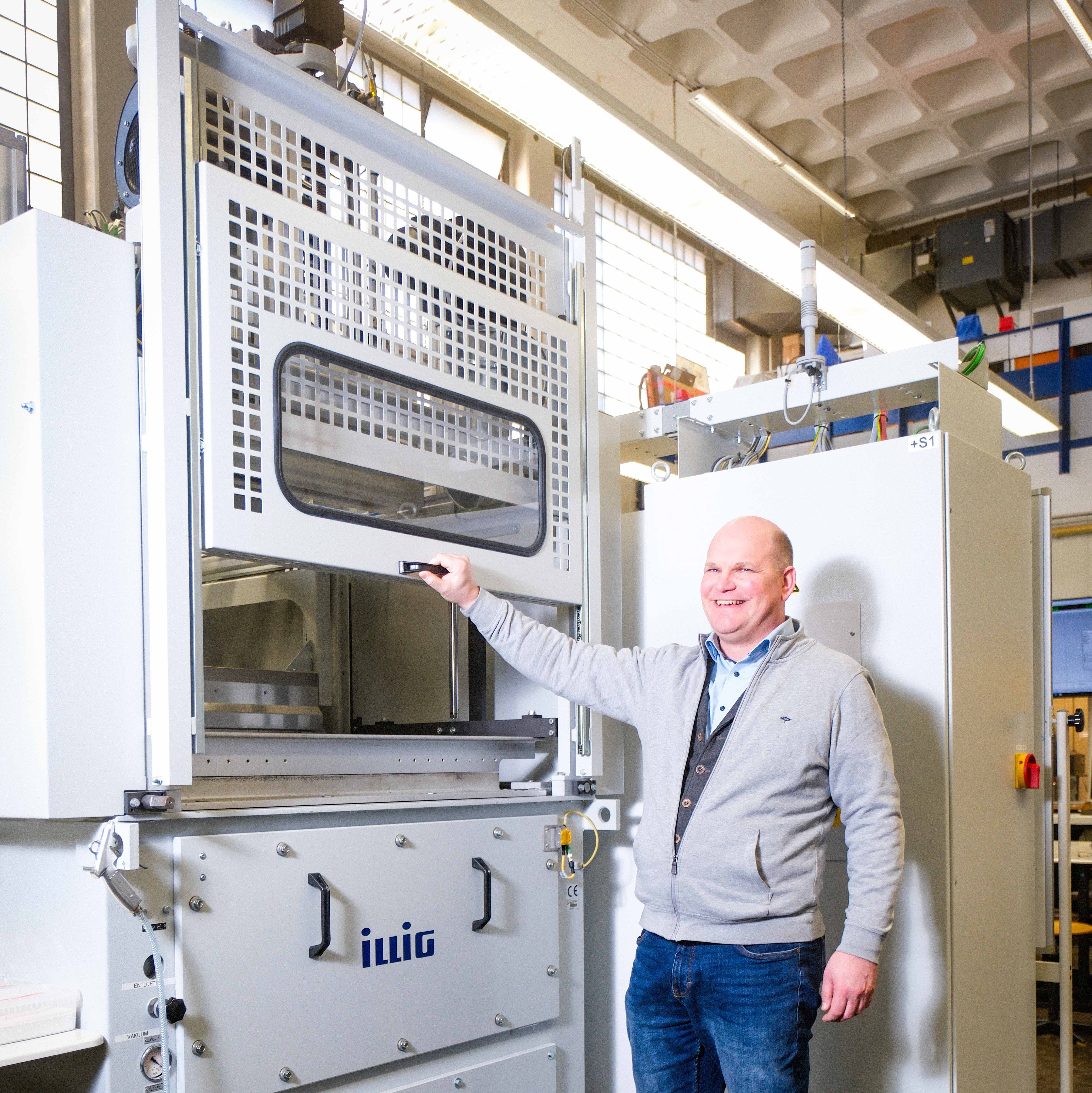 Ein Mann öffnet eine Schiebetür einer Maschine nach oben