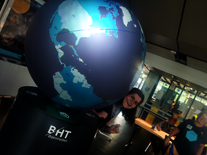 Eine junge Frau steht vor einem großen, blau leuchtenden Globus.