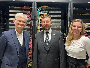 Drei Personen posieren vor Serverschränken