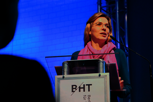 Eine Frau steht an einem Rednerpodest mit der Aufschrift „BHT“.