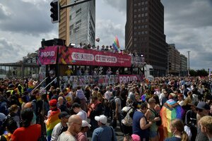 Demonstrationszug in der Innenstadt von Berlin: Eine Person schwenkt eine Regenbogenflagge, ein Bus trägt die Aufschrift „Liebe tut der Seele gut“