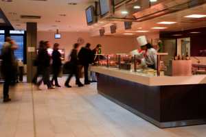 Eine Menschenschlange vor der Essensausgabe einer Großküche.