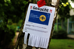 Ein Ausdruck auf Briefpapier mit der Aufschrift „!! Gesucht !!“ ist an einem Baum angebracht.