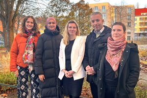 Vier Personen stehen draußen vor herbstlicher Kulisse