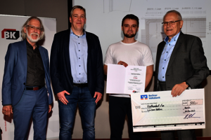 Vier Männer stehen nebeneinander. Einer hält eine Urkunde, einer hält einen Gutschein in der Hand.