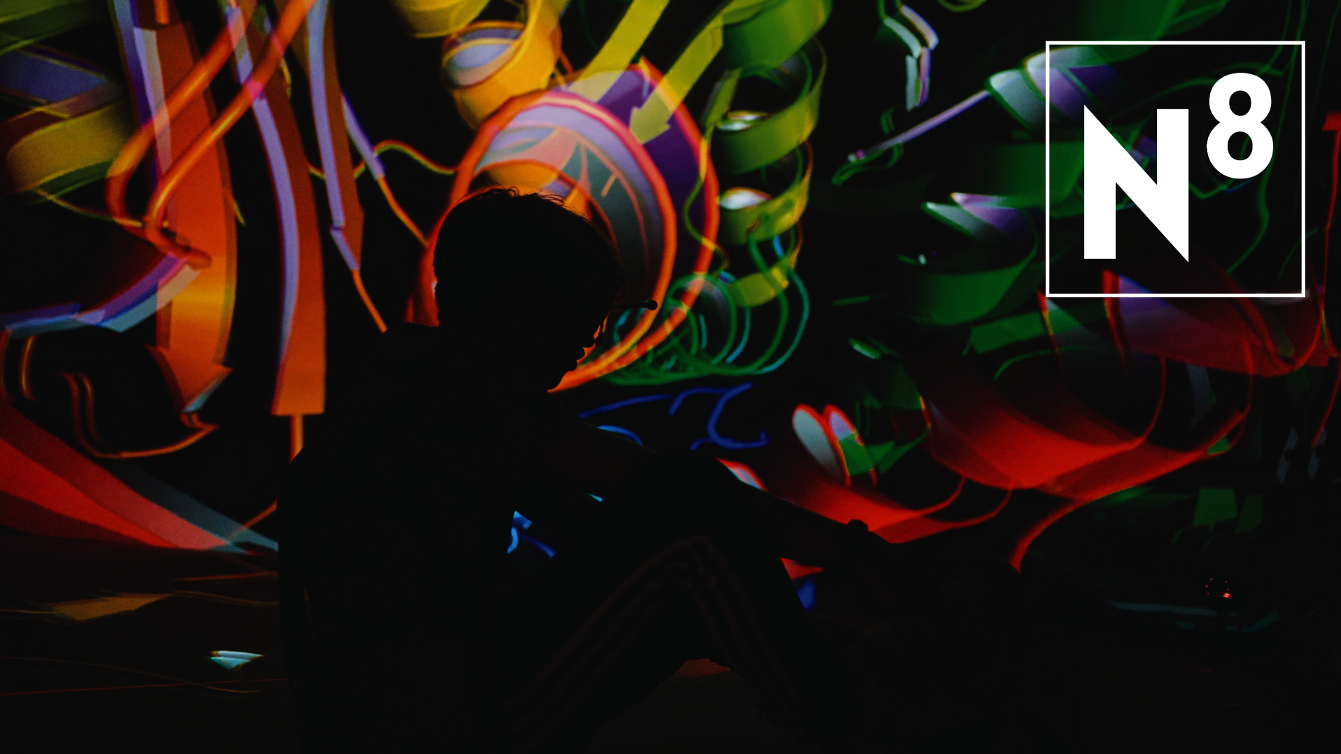 Schatten eines sitzenden Menschen mit VR-Brille vor bunter abstrakter Projektion, Text: Lange Nacht der Wissenschaften, 28. Juni 2025, 17-24 Uhr 