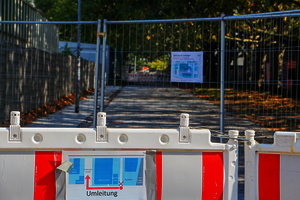 Bauzaun und eine Absperrung vor einem Gehweg.