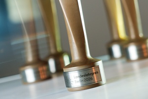 Fünf Trophäen, auf der Plakette der Trophäe im Vordergrund steht "Landeslehrpreis Berlin 2026"