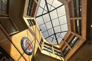 Blick nach oben in Foyer mit verglaster Decke, an einer Wand das Logo der Lakehead University