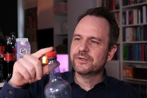 Mann zeigt auf Deckel einer PET-Flasche