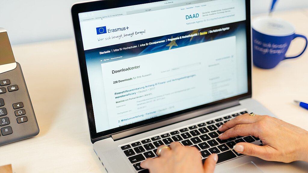 Laptop, zwei Hände auf der Tastatur, auf dem Bildschirm ist ein Formular für das Erasmus+-Programm erkennbar
