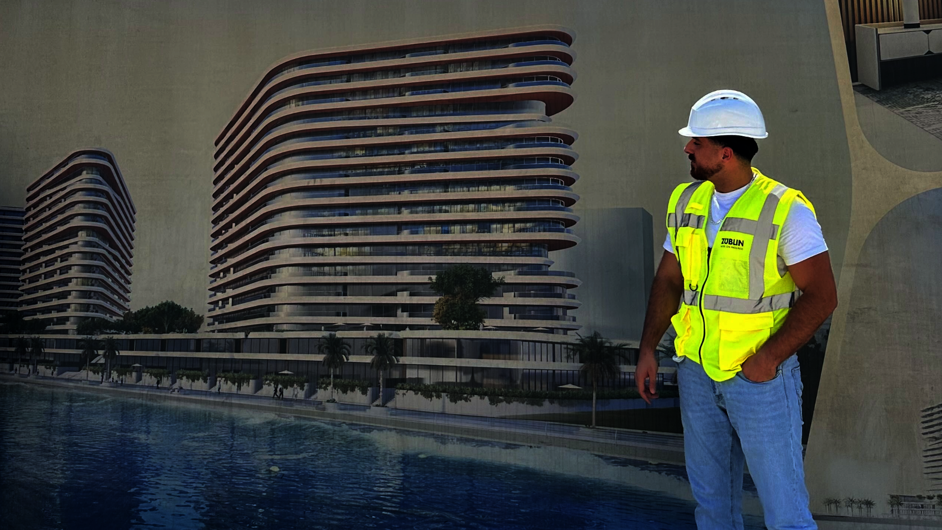 Mann mit Bauhelm und Warnweste steht vor dem Entwurf eines Gebäudes