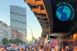 Junge Menschen laufen unter einer S-Bahn-Brücke an einer viel befahrenen Straße in Berlin