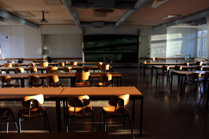 Menschenleerer Raum mit Tischen und Stühlen, die auf eine Tafel ausgerichtet sind