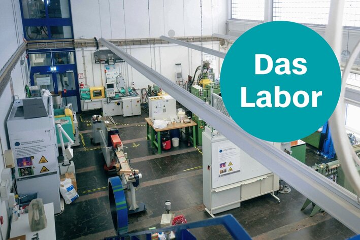 Blick auf das Labor für Kunststoffverarbeitung und -prüfung von oben, zu sehen sind zahlreiche Maschinen und Geräte in eine hellen, lichtdurchflutetem Raum. Text: Das Labor