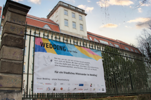 Eines der bunten Banner von „Wedding zeigt Farbe“ vor Haus Beuth der BHT.