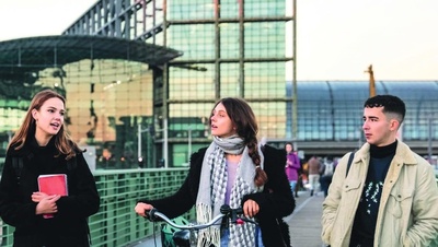 Drei junge Menschen auf einer Brücke vor dem Berliner Hauptbahnhof