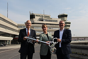 Schlüsselübergabe in Tegel: Gudrun Sack, Philipp Bouteiller und Werner Ullmann mit dem symbolischen Schlüssel vor dem ehemaligen Flughafen