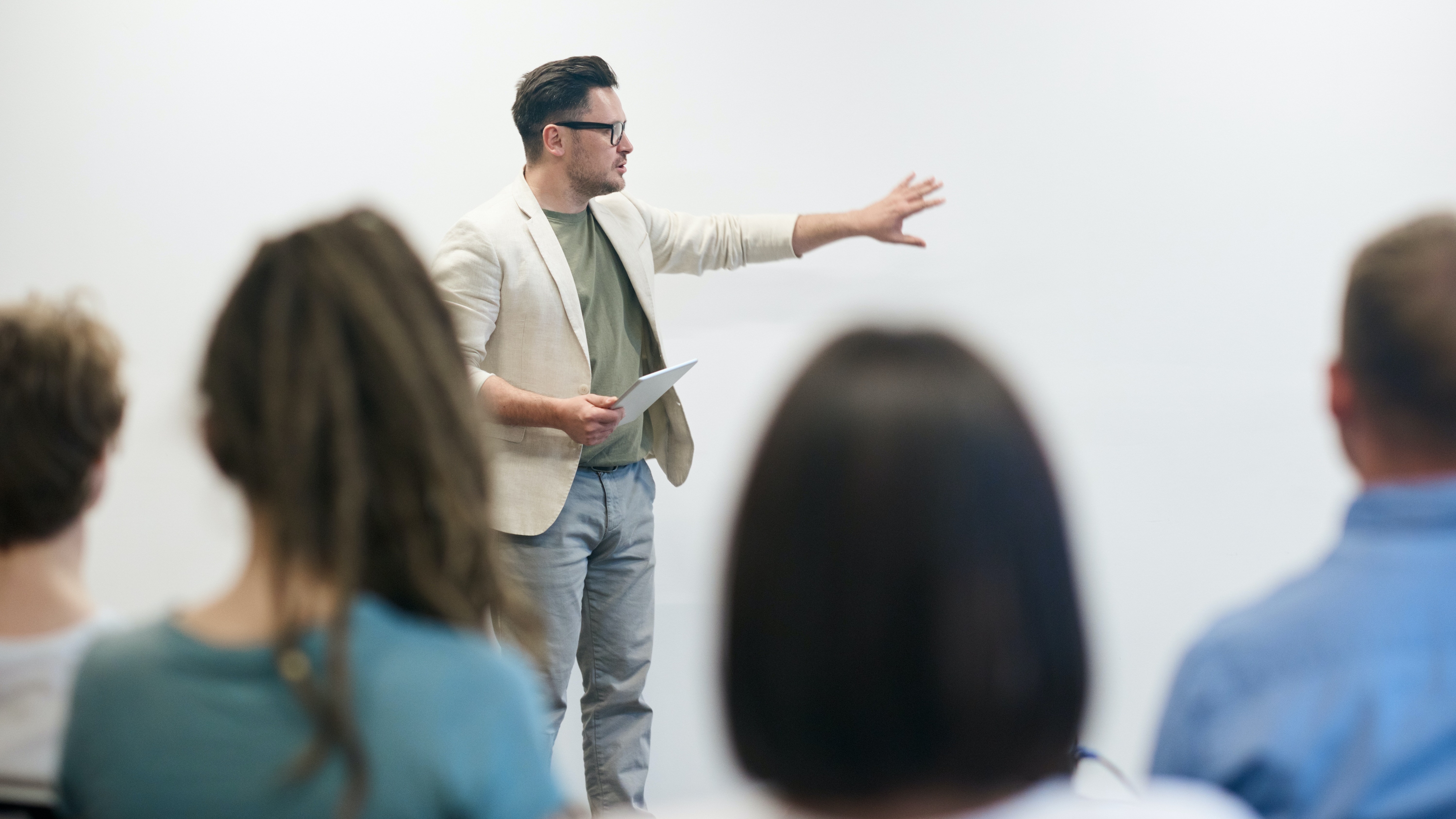 Ein Mann hält eine Präsentation, Zuschauende sind von hinten zu sehen