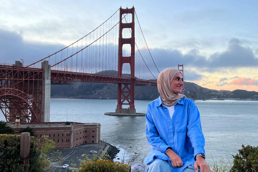 Eine Frau sitzt vor der Golden Gate Bridge
