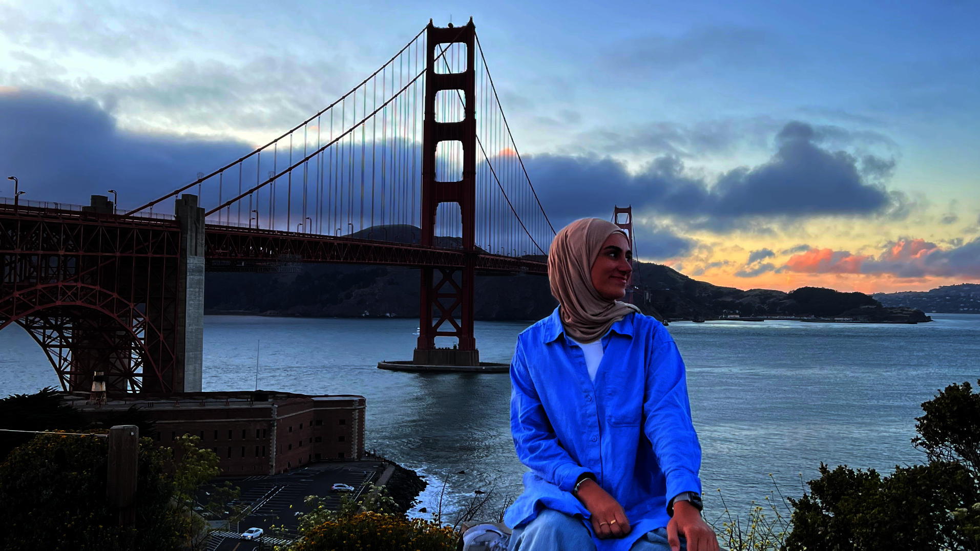 Eine Frau sitzt vor der Golden Gate Bridge