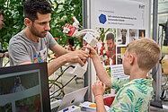 Ein Mann zeigt einem Kind einen Roboterarm.